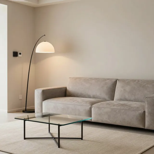 Minimalist modern oturma odasında bej kanepe, cam sehpa ve yay lamba.